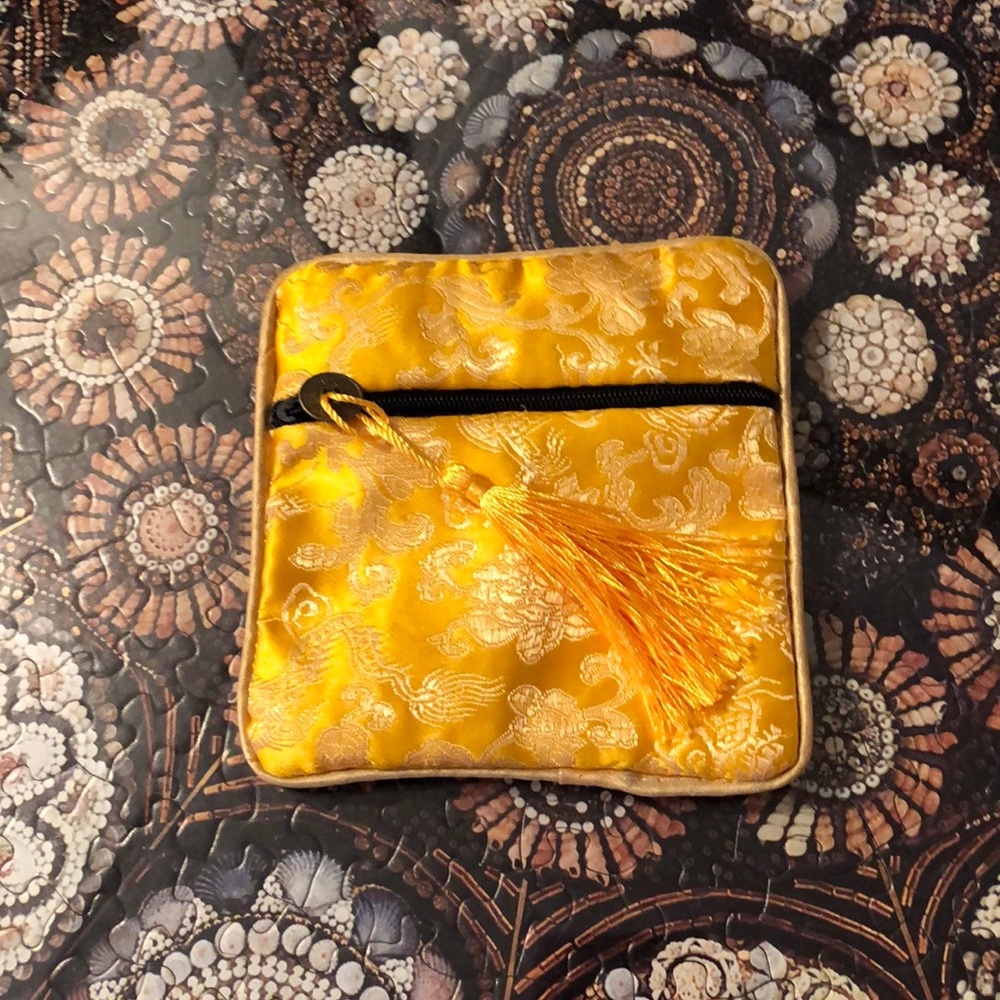 Patterned gold fabric mini zippered pouch.